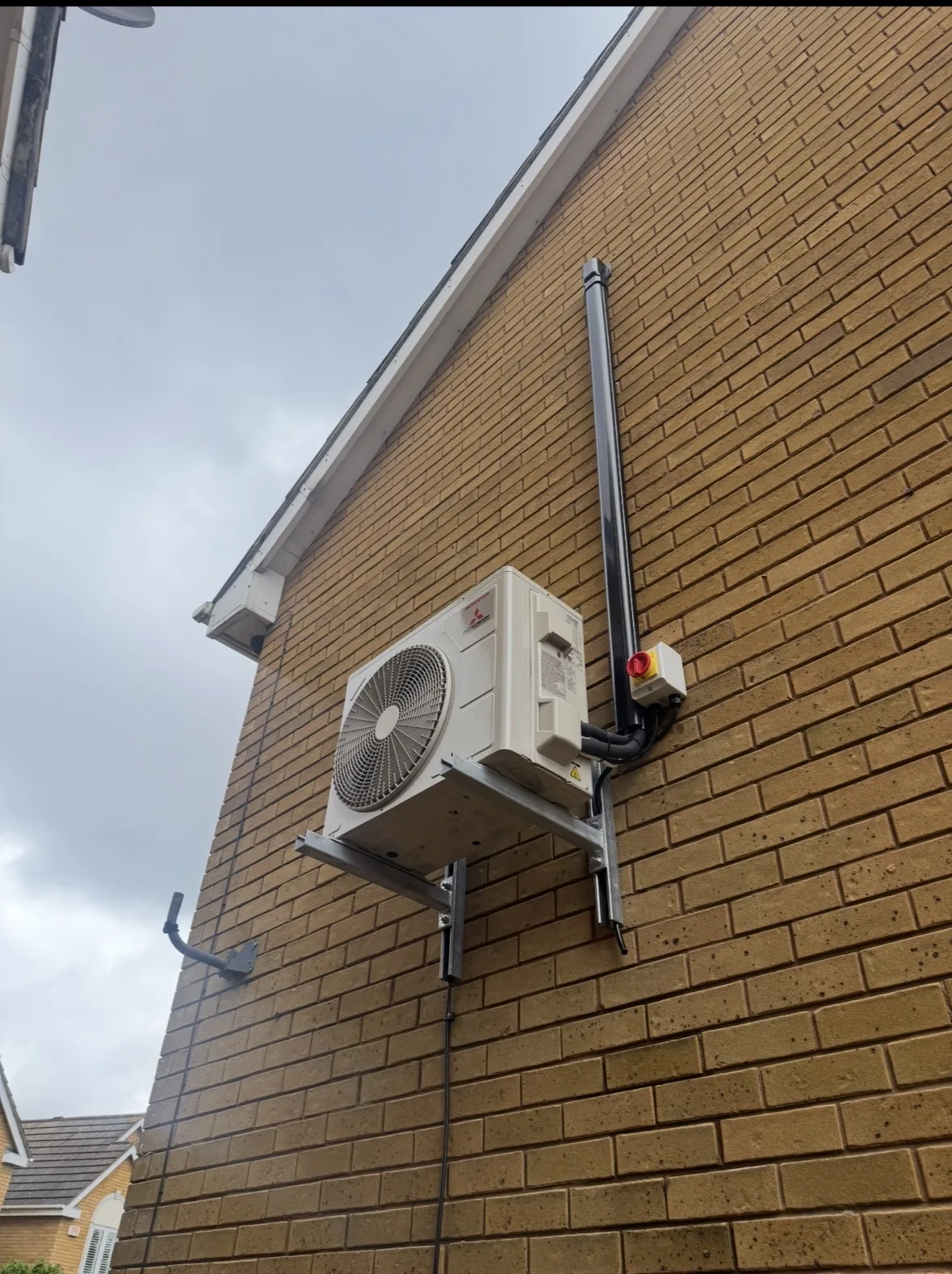 Outdoor air conditioning condenser unit installed on a brick house wall with neat pipework by Aervue